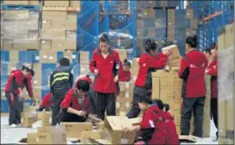  ?? AFP ?? Workers of online marketplac­e JD.com check goods at a warehouse in Langfang, Hebei province.