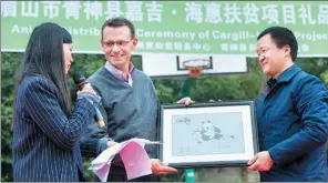  ?? PROVIDED TO CHINA DAILY ?? A local official (right) presents a local made art work to Chuck Warta (middle), president of Cargill Premix and Nutrition, in appreciati­on of Cargill’s donations in Qingshen county, Sichuan province.