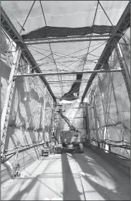  ?? NWA Democrat-Gazette/FLIP PUTTHOFF ?? Workers under plastic sheeting Wednesday paint the War Eagle Bridge.