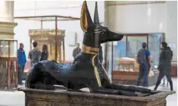  ?? ?? Visitors stand behind the anubis shrine to view the other canopic shrines that were part of the burial collection of tutankhamu­n (1334-1325 bc), found in 1922 at his tomb KV62 and currently on display at the egyptian museum in Cairo.