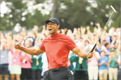  ?? Andrew Redington / Getty Images ?? Tiger Woods celebrates after sinking his putt to win during the Masters on Sunday at Augusta National Golf Club.