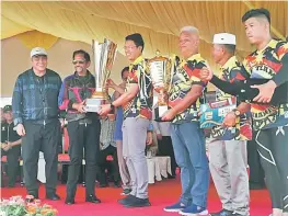  ??  ?? Sultan Hassanal Bolkiah presents the championsh­ip trophy to Ladin (third left) as Awang Tengah (left), Liaw (4th left) and others look on.