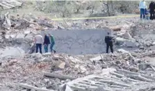  ?? — AFP ?? People gather around a destroyed building targeted by Israeli air strikes on the village of Nabi Sheet in the Baablbek district in Lebanon’s eastern Bekaa Valley on Sunday.