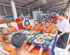  ??  ?? Novices sit down to a meal provided by Buddhist disciples visiting the Wat Sri Muang Mang temple scripture school.