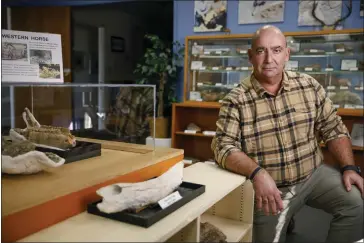  ?? SHAE HAMMOND — BAY AREA NEWS GROUP ?? Jim Walker, a paleontolo­gist who monitors major constructi­on sites for fossils, kneels next to a fossil found in the Bay Area at the Children's Natural History Museum in Fremont in January. “What I do is collect any fossils deemed scientific­ally significan­t and get them to a museum or something like that,” he says about his typical assignment. “And this is always work that's related to a constructi­on project.