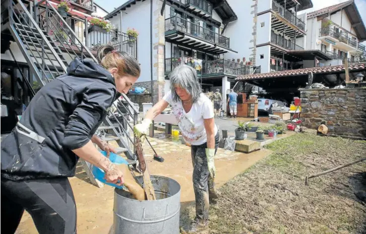  ?? ?? Dos vecinas de Bera retiran el barro recogido en sus viviendas situadas junto a la regata Zia.