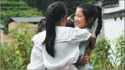  ?? ZHANG DUAN / XINHUA ?? The daughter (right) hugs her friend in the village, and bids goodbye.