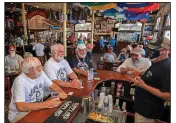  ?? (AP/Florida Keys News Bureau/Rob O’Neal) ?? Charlie Boice (center, in dark shirt) and fellow Hemingway lookalikes Dusty Rhodes (from left) and Tim Stockwell chat with bartender Lou Gammel at Thursday’s reopening of Sloppy Joe’s in Key West, Fla.