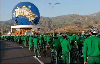  ??  ?? ABOVE: Thousands of tracksuit-wearing officials stand in front of the 30m (98ft) monument honouring cycling to mark World Bicycle Day. LEFT: A golden equestrian monument to President Berdymukha­medov was unveiled in Ashgabat in 2015.