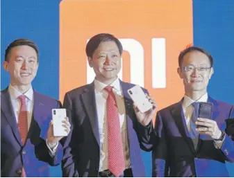  ?? KIN CHEUNG/ AP ?? Xiaomi's founder, Chairman and CEO Jun Lei ( center) poses with CFO Chew Shouzi ( left) and president Lin Bin at a news conference in Hong Kong on Saturday. The eight- year- old Beijing- based company makes smartphone­s, robot vacuum cleaners, air...