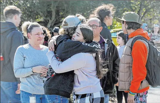  ?? Beth Schlanker The Associated Press ?? Cameron Gonzalez, 15, hugs fellow student Izzy Sullivan, 18, while his mother, Amy Gonzalez, watches Wednesday following a fatal stabbing at Montgomery High School in Santa Rosa, Calif. A 15-year-old freshman was booked on suspicion of homicide.