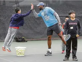  ?? Melissa Phillip / Houston Chronicle ?? Conley Feng, 14, shows off his hops while high-fiving Rockets player Tarik Black during the Kids Day event Sunday at River Oaks Country Club.