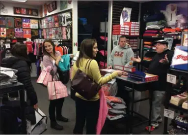  ?? CHAD FELTON — THE NEWS-HERALD ?? Laurel Gans, pointing, and her sister, Stephanie, holding pink bags, take advantage of Black Thursday deals at Hometown Clothing Co. at the Great Lakes Mall on Nov. 22. To the right is the store’s owner, Tony Pines.