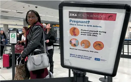  ?? REUTERS ?? A woman looks at a health advisory sign about the dangers of the Zika virus as she lines up for a security screening at Miami Internatio­nal Airport. Zika is now being spread by mosquitoes in Florida, but state officials do not expect to see a...