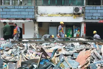  ??  ?? Left: Workers tear down unauthoriz­ed exterior walls on Tonglihou street, aka “Dirty street”, in Beijing’s Sanlitun. Right: