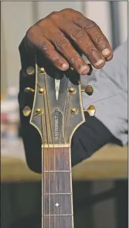  ??  ?? Resting his hand against the head of his acoustic guitar, Holmes’ fingertips show the wear after years of performing without a pic at the Blue Front Cafe.