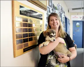  ?? NEWS PHOTO EMMA BENNETT ?? Katie Ayres, executive director at the Medicine Hat SPCA, holds corgi cross puppy Arwen in front of the donor walll at the shelter.