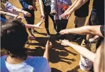  ??  ?? Players in the Clairemont Girls Fastpitch league put their hands together without touching as practice ends. Registrati­on in the league is down slightly this year.