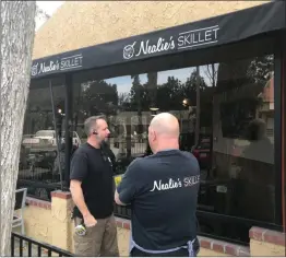  ?? Perry Smith/The Signal ?? Rick Grimsley, left, of B & D Glass, and Neal Scott, of Nealie’s Skillet, discuss repairs to the window of the restaurant, which was broken into at around 1:05 a.m. on Wednesday. A security camera at the restaurant, which had just previously celebrated...