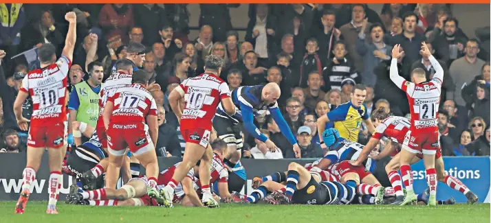  ??  ?? How the West was won: Ed Slater, hidden beneath a pile of bodies, is driven over the Bath line to score the Gloucester try deep into injury time that set up a one-point victory yesterday