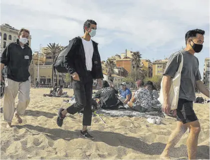  ?? JORDI OTIX ?? Tres jóvenes con mascarilla, ayer, en la playa de La Barcelonet­a.