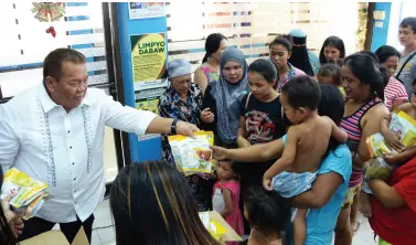  ?? BING GONZALES ?? COUNCILOR Edgar Ibuyan Sr., president of the Liga ng mga Barangay Davao Chapter and chair of Barangay 5-A in Poblacion District, gives food items to his constituen­ts affected by the recent fire that hit Bankerohan area. The fire victims are now taking temporary shelter at the barangay covered court.