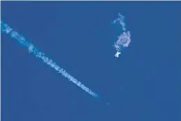 ?? CHAD FISH/AP ?? The remnants of a large balloon drift above the Atlantic Ocean, just off the coast of South Carolina, with a fighter jet and its contrail seen below it. The incursion by a Chinese spy balloon across U.S. territory raised concerns among Americans about a possible escalation in spying and other challenges from a global rival.