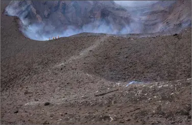  ?? (AP/Saul Santos) ?? Scientists walk near the edge of the crater Wednesday at the Cumbre Vieja volcano in the Canary Islands of La Palma, Spain.