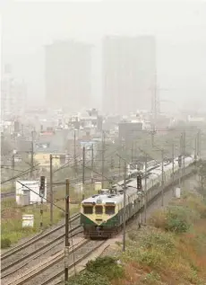  ?? — AFP ?? A local train passes by as dust covers the skyline on the outskirts of New Delhi, in Ghaziabad, Uttar Pradesh on Thursday.