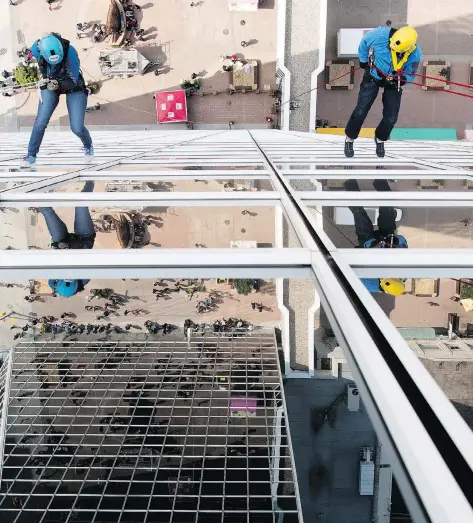  ?? TROY FLEECE ?? Madeline Pass, left, and her father, Chris Pass, head down the side of Hill Tower II during the Easter Seals Drop Zone event in Regina.