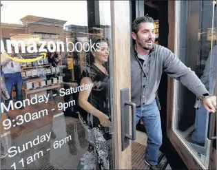  ?? AP PHOTO/ELAINE THOMPSON ?? In this Nov. 3, 2015, file photo, employees smile as they unlock and open the door to the first customers at the opening day for Amazon Books, the first brick-and-mortar retail store for online retail giant Amazon. Although Amazon already dominates...