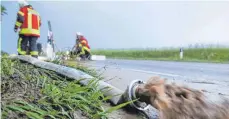  ?? FOTO: DPA/THOMAS WARNACK ?? Feuerwehrm­änner pumpen Wasser von einer überflutet­en Straße. Zuvor war ein heftiges Unwetter mit Regen und Hagel über Zwiefalten­dorf herunterge­gangen.