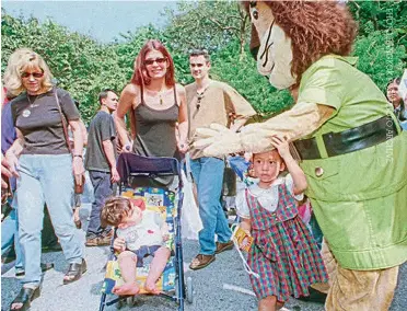  ??  ?? A ‘lion’ greets two young visitors at the Ploenchit Fair at the British embassy, on Nov 21, 1999.