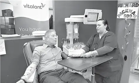  ?? Antonio Perez/ Chicago Tribune/TNS ?? Donor care specialist Nora Martinez holds out a cake with candles as Richard Packman, 74, blows them out while donating platelets at Vitalant in the Thompson Center on Friday, Oct. 12, 2018. This was the 500th time Packman had donated blood or platelets.