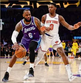  ?? Ronald Martinez / Getty Images ?? LeBron James, left, of the Lakers drives around RJ Barrett of the Knicks on Saturday. James had a triple-double and Barrett scored 36 points.