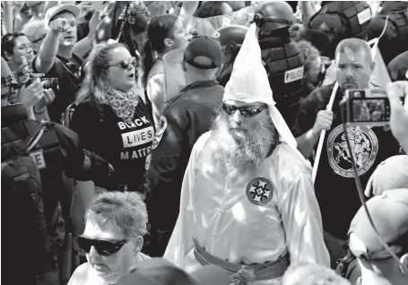  ?? Associated Press ?? n Members of the KKK are escorted by police past a large group of protesters on July 8 during a KKK rally in Charlottes­ville, Va. Some white Southerner­s are again advocating for what the Confederac­y tried and failed to do in the 1860s: Secession from...