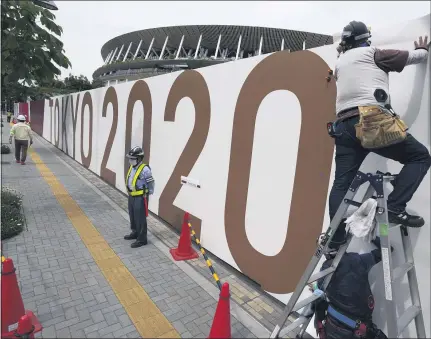  ?? EUGENE HOSHIKO — THE ASSOCIATED PRESS ?? Workers last week paste the overlay on the wall of the National Stadium, where the opening ceremony and many other events are scheduled for the postponed Tokyo 2020 Olympics. Roads are being closed off around Tokyo venues, including the new $1.4 billion National Stadium where the opening ceremony is set for July 23.