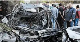  ?? SANA/AP ?? Syrians gather next to a car hit Friday by Army of Islam shelling of Damascus.