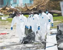  ?? Brendan Smialowski, AFP/Getty Images ?? Workers recover a body Thursday in Marsh Harbour on Great Abaco Island.