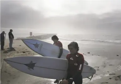  ?? Photos by Lea Suzuki / The Chronicle ?? Beck Adler of Venice (right) and Rolando Stanley of Mexico carry surfboards on Mavericks Beach.