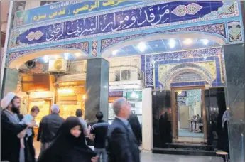  ?? MCT via Getty Images ?? Signs of economic life: Iraqis stroll through the Baghdad district of Kadhemiya on April 1, where a Shiite Muslim shrine draws worshipers and shops and restaurant­s are often packed with customers.