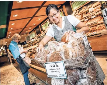  ?? FOTO: ANDREAS ENDERMANN ?? In der Filiale der Bäckerei Schüren in Düsseldorf wird Brot vom Vortag zu günstigere­n Preisen angeboten. Mitarbeite­rin Chow Har Verbeeten sortiert die Ware. Die Nachfrage ist groß.