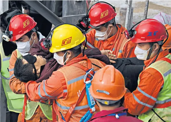  ??  ?? Rescuers yesterday carry one of the 11 miners to safety from the Hushan gold mine, Shandong province, east China. The man wears a black mask to protect his eyes from the light after a fortnight in darkness.