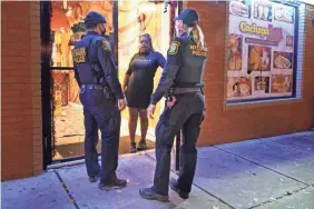  ?? SETH WENIG/AP ?? Police officers remind a woman in the doorway of a Newark, N.J., restaurant of the new curfew and dining regulation­s Nov. 12.