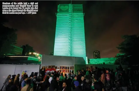  ??  ?? Members of the public hold a vigil and commemorat­ion near Grenfell Tower in west London at to honour the 71 people who died when a fire ripped through the Grenfell tower block in London one year ago. — AFP photo