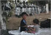  ?? MARCO UGARTE — THE ASSOCIATED PRESS ?? With a line of Mexican National Guardsmen behind them, a couple of migrant children are camped out on the Mexican shore of the Suchiate river on the border with Guatemala, near Ciudad Hidalgo, Mexico, Monday.