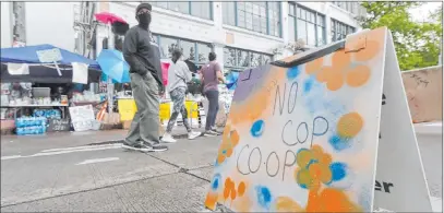  ?? Ted S. Warren The Associated Press ?? People walk near what is being called the “No Cop Co-op” where protesters and others can get free food and other supplies Thursday inside what is being called the “Capitol Hill Autonomous Zone” in Seattle.