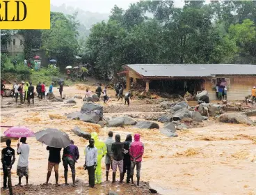  ?? SAIDU BAH / AFP / GETTY IMAGES ?? Bystanders look on as floodwater­s rage in Freetown on Monday, after landslides struck the Sierra Leone capital.