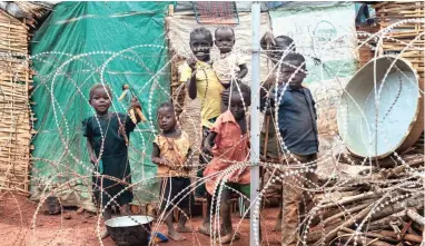  ?? PICTURE: AP ?? LIVING ON THE EDGE: A family stands behind the razor-wire that surrounds the UN’s protected camp in Wau, South Sudan, which since clashes in April is now the most congested internally displaced camp in the country, with almost 40 000 inhabitant­s.