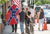  ?? ANDRE TEAGUE/BRISTOL HERALD COURIER VIA AP ?? A man wears a Confederat­e flag while walking in Marion, Va., earlier this month. Defense leaders have for weeks been tied over the issue of banning the Confederat­e flag.